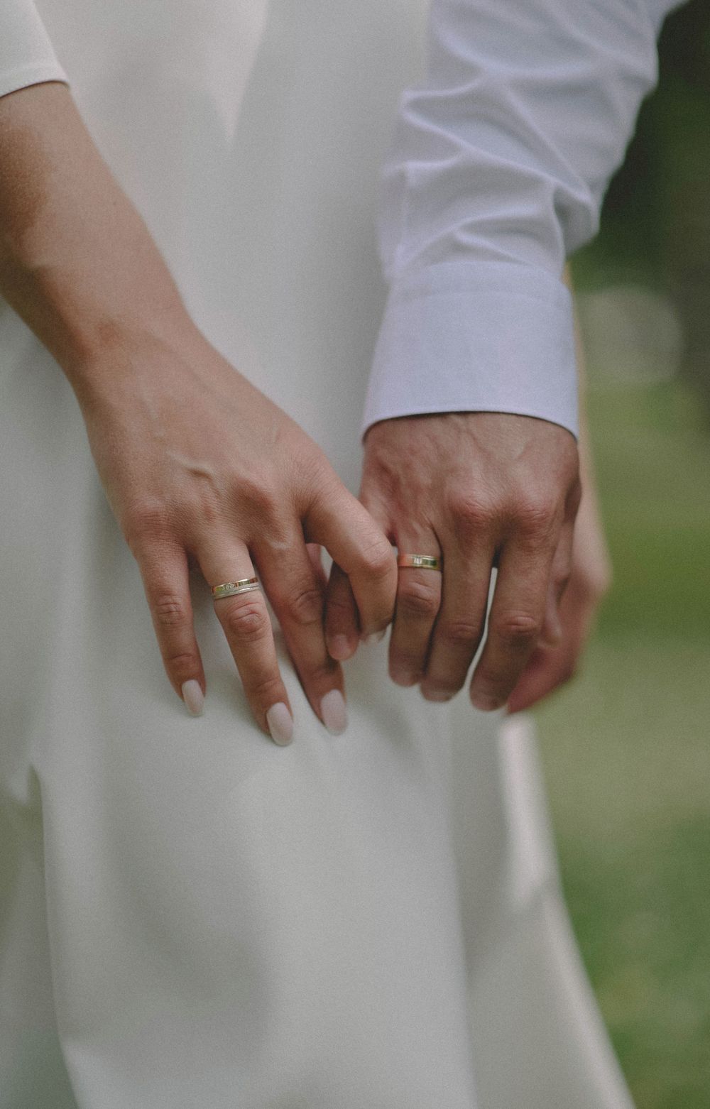 Mãos de um casal de noivos com alianças de ouro